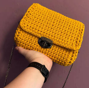 Handmade mustard-yellow crochet crossbody bag with a black-nickel clasp and chain strap