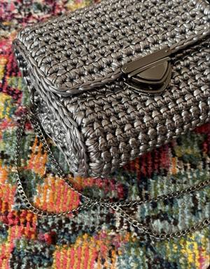 Close-up of the silver metallic crochet box bag, showing the stitch texture of the ribbon yarn and the black-nickel clasp